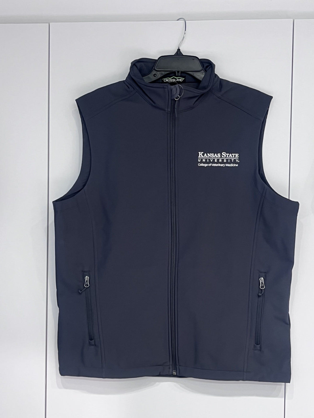 A dark gray soft shell zip-up vest with a high collar, featuring the 'Kansas State University' logo embroidered on the left chest. The vest has two vertical zippered pockets on the lower front and is photographed flat against a light off-white background.