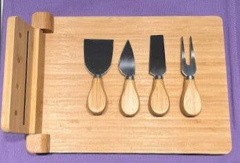 Set of four cheese knives on a bamboo board with a purple background.