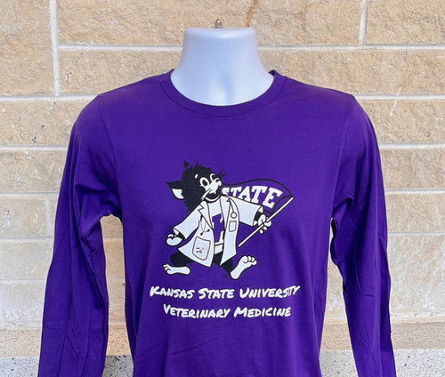 Purple long-sleeve shirt with a Labcoat Willie graphic and "Kansas State University Veterinary Medicine" text on a mannequin against a brick wall.