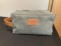 A gray toiletry bag with a brown leather handle and a brand leather label that reads 'Kansas State University College of Veterinary Medicine'.