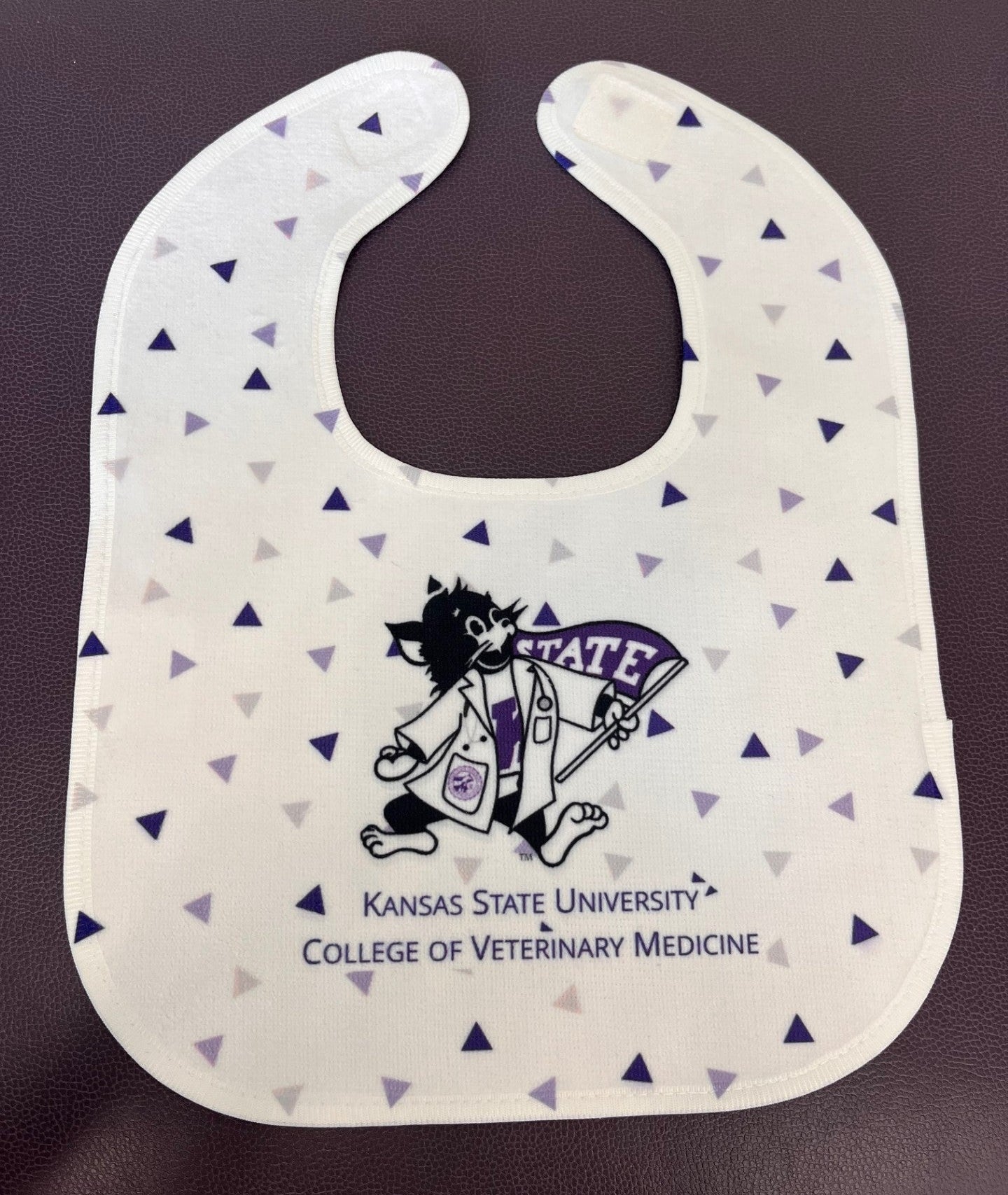 Bib with Kansas State University College of Veterinary Medicine Labcoat Willie logo on a white background with a dark and light purple mini triangle pattern. 