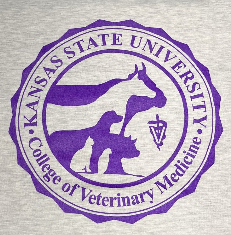 A light heather gray sweatshirt featuring a large purple circular graphic of the Kansas State University College of Veterinary Medicine logo