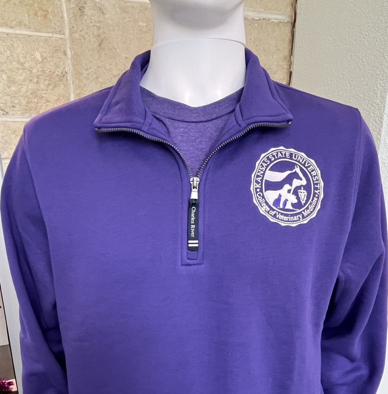 Purple quarter zip sweatshirt with white College of Veterinary Medicine seal logo on left chest. 