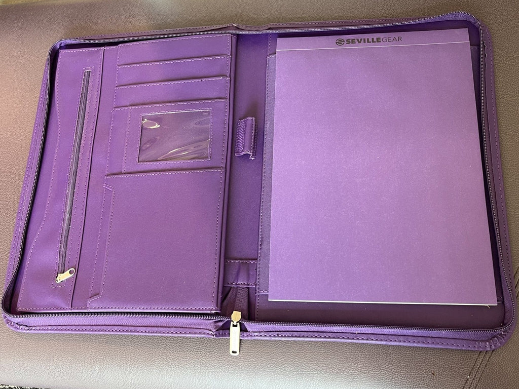 A purple zippered document organizer or tablet sleeve laid open on a beige upholstered chair, showing interior pockets, a clear ID window, and a large front pocket