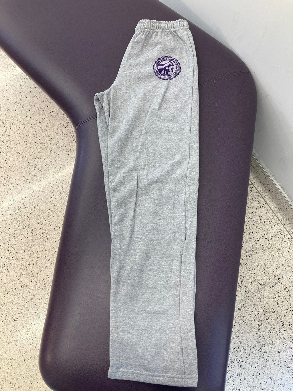 Customized Gildan Heavy Blend Open Bottom Sweatpants in Sports Grey with a purple CVM seal on the upper left thigh.