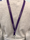 A person wearing a light gray sweatshirt, wearing a purple Kansas State University lanyard with a key ring and keychain.