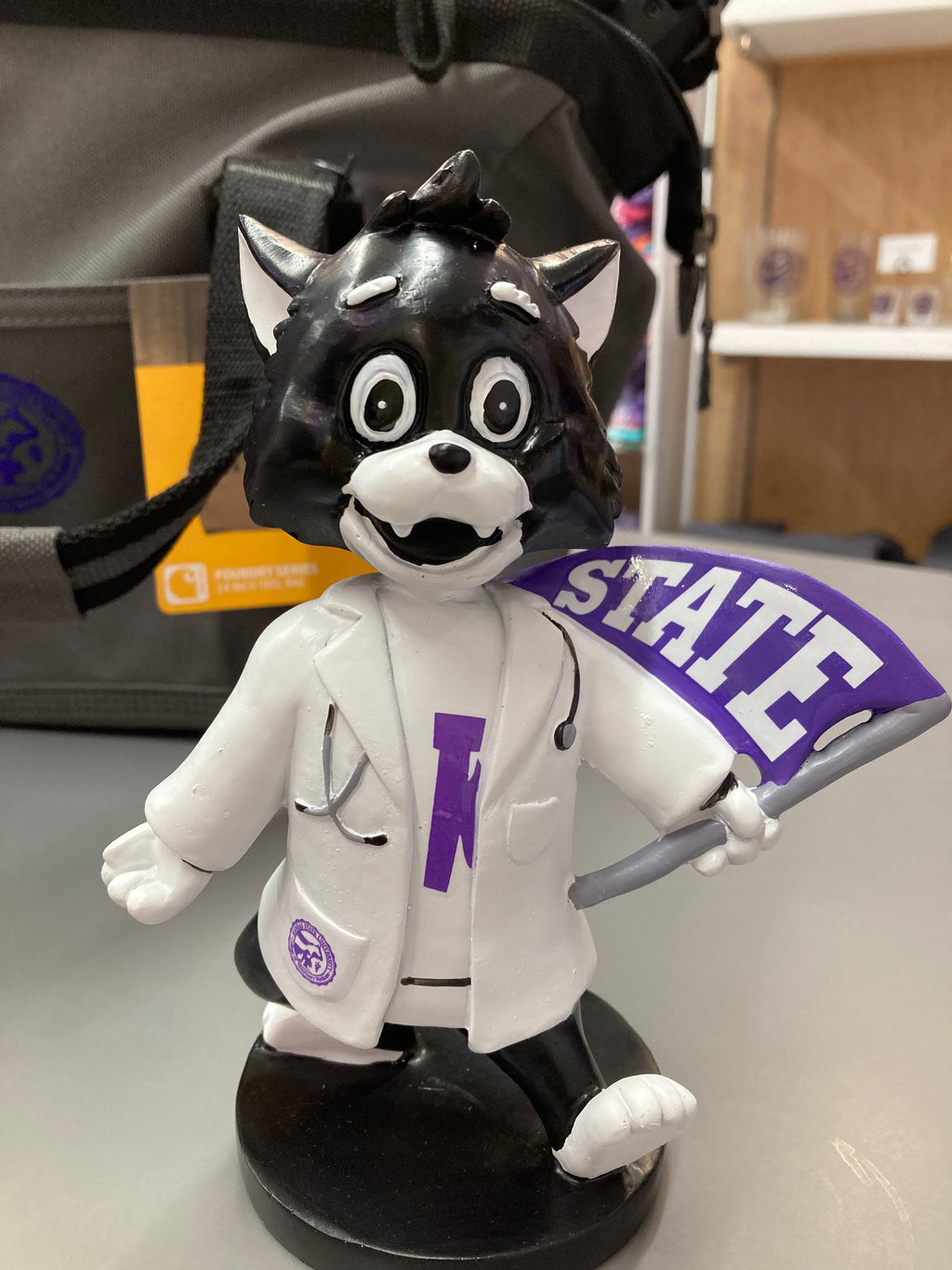 A customized Labcoat Willie Bobble Head wearing a white lab coat with a 'STATE' flag element, seated on a bobblehead base.
