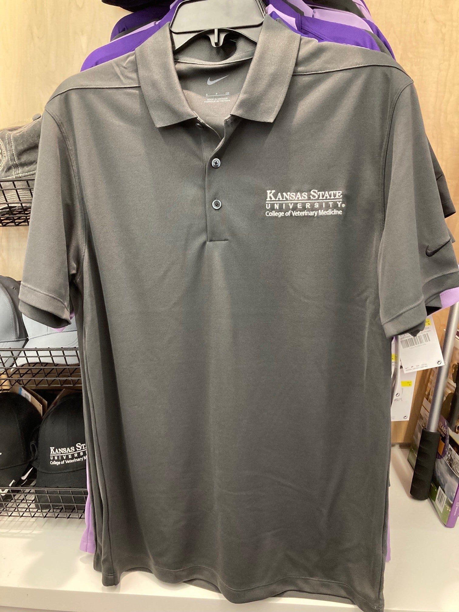 A grey Nike polo shirt with white CVM logo on the upper left side. 
