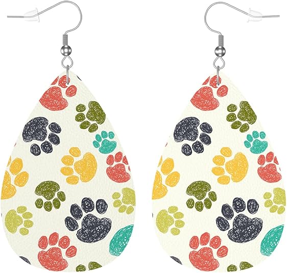 A pair of beige leather earrings with multicolored paw print patterns.
