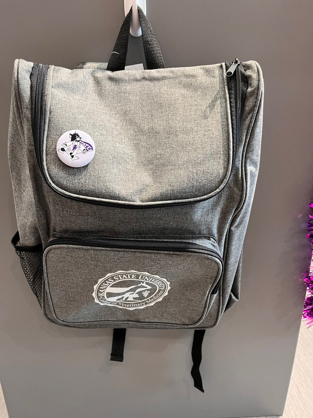 Gray bag with a round button featuring a cartoon Labcoat Willi with a light purple background. 