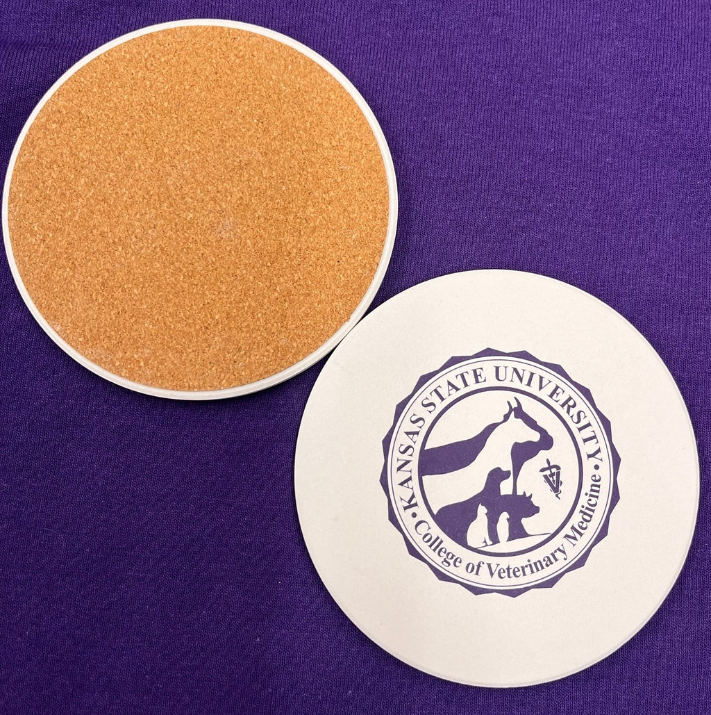 Round coaster with Kansas State University College of Veterinary Medicine seal in dark purple against a white background color. It also shows the cork textured underside of the coaster. 
