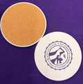 Round coaster with Kansas State University College of Veterinary Medicine seal in dark purple against a white background color. It also shows the cork textured underside of the coaster. 