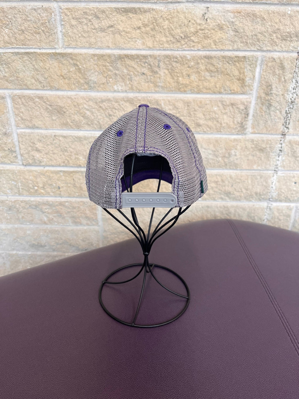 Back view of trucker hat in purple and grey with embroidered CVM seal in grey 