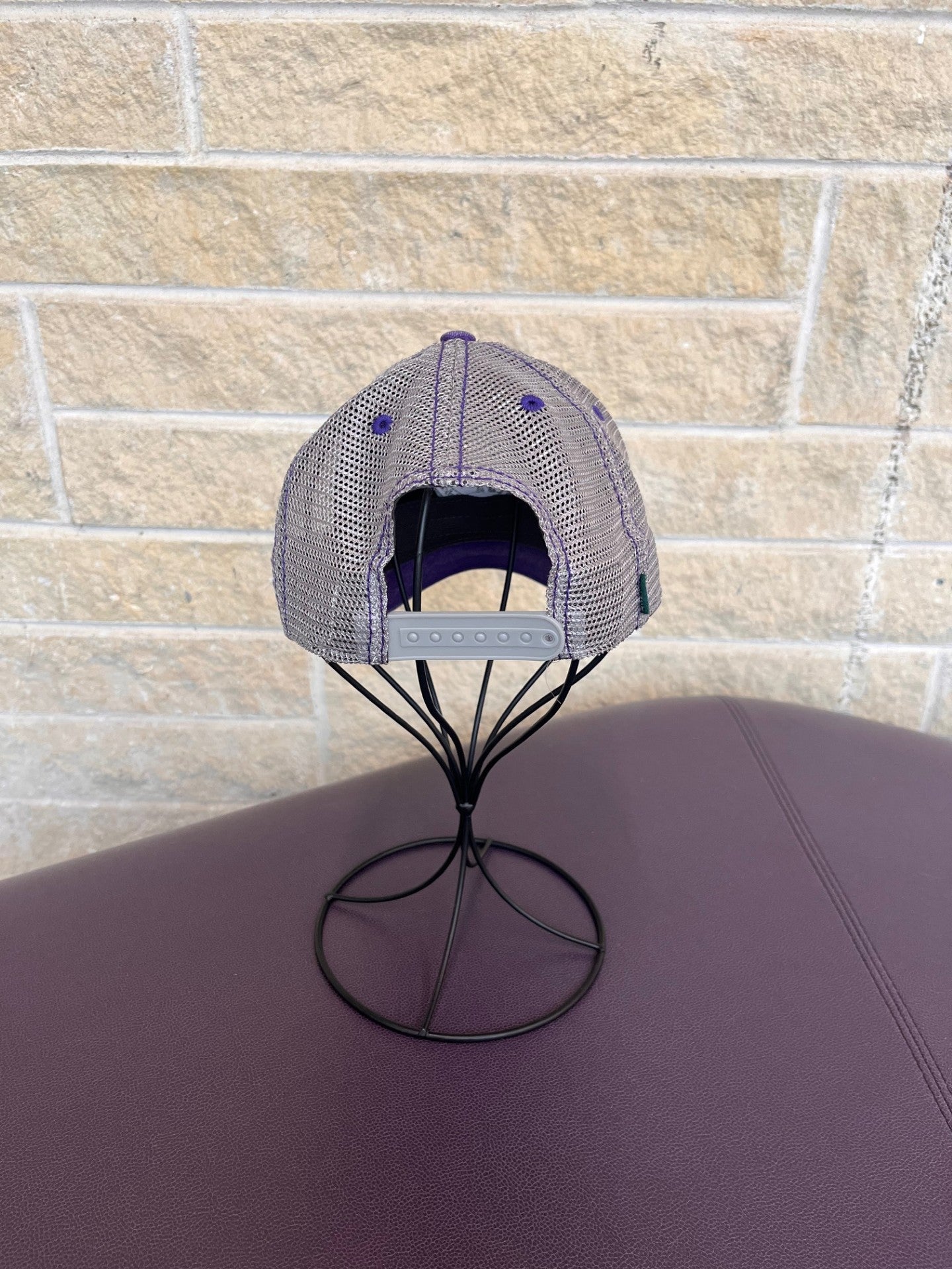 Back view of trucker hat in purple and grey with embroidered CVM seal in grey 