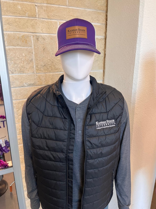 Mannequin wearing a black puffer vest and gray shirt with a purple and white trucker hat with Kansas State University College of Veterinary Medicine logo patch.
