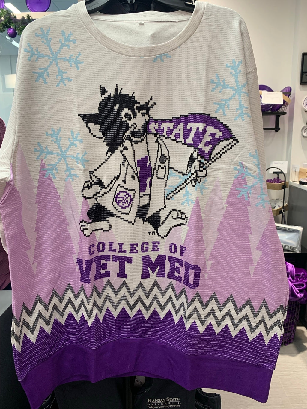 A purple, pink, and white striped Christmas sweatshirt featuring a graphic of Labcoat Willie surrounded by blue snowflakes. 