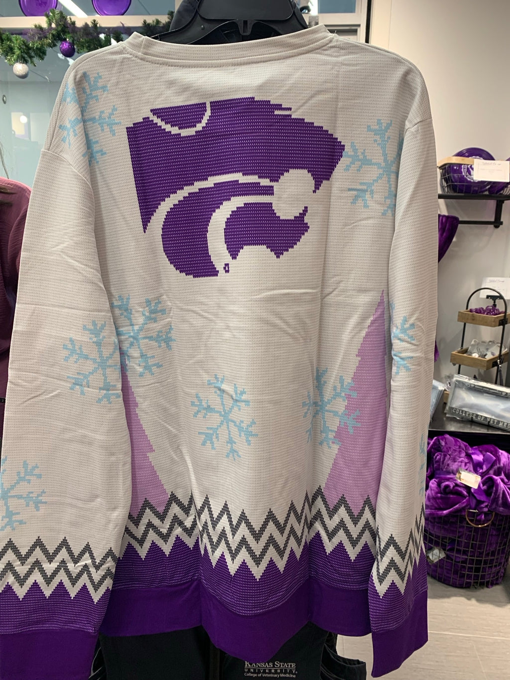 A rear few of the purple and white Christmas shirt featuring a dark purple Wildcat logo in the center of the upper back. 