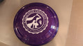 A purple frisbee with the white seal of the College of Veterinary Medicine in the center. 