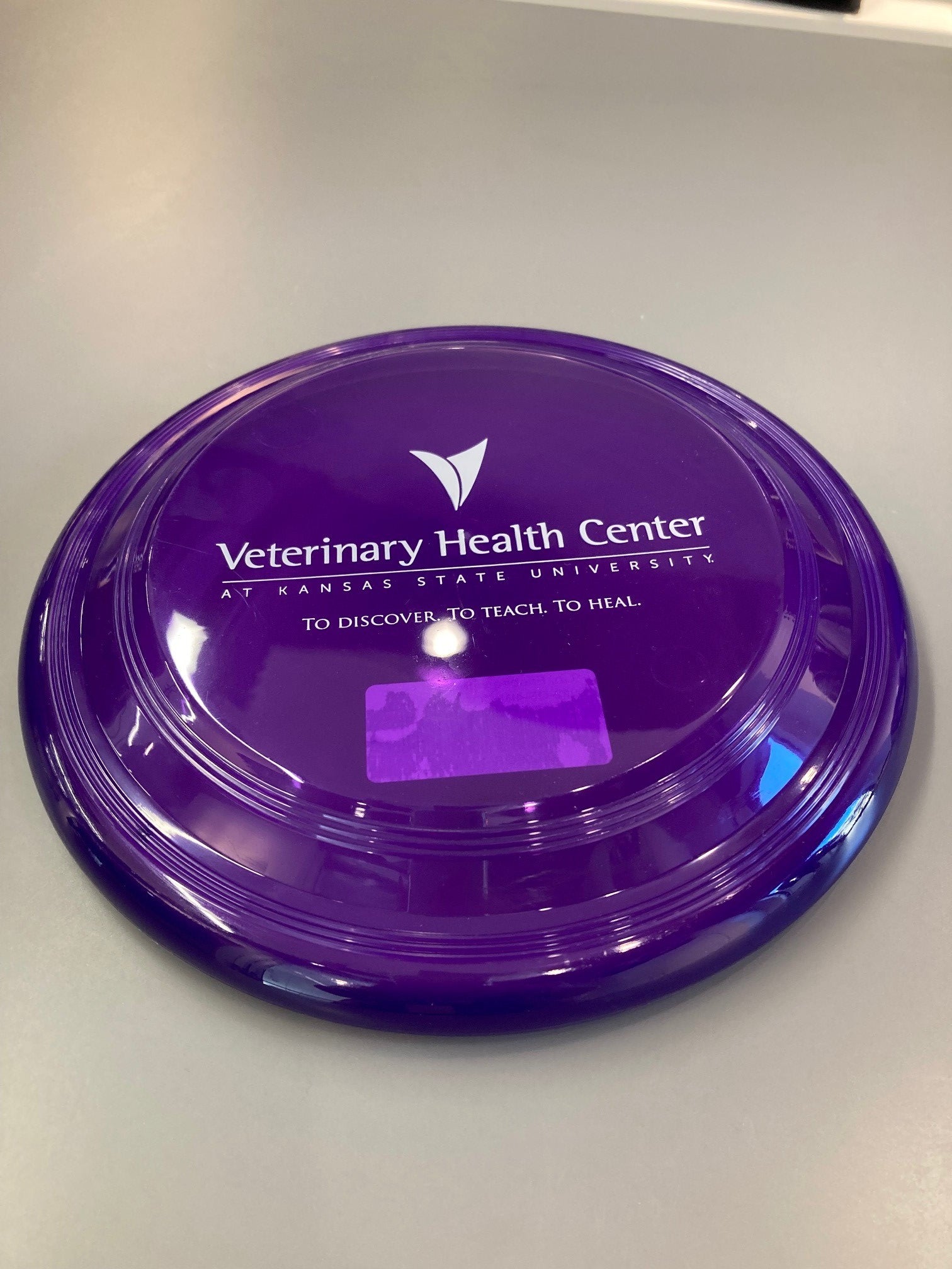A purple frisbee with the white Veterinary Health Center logo in the center. 