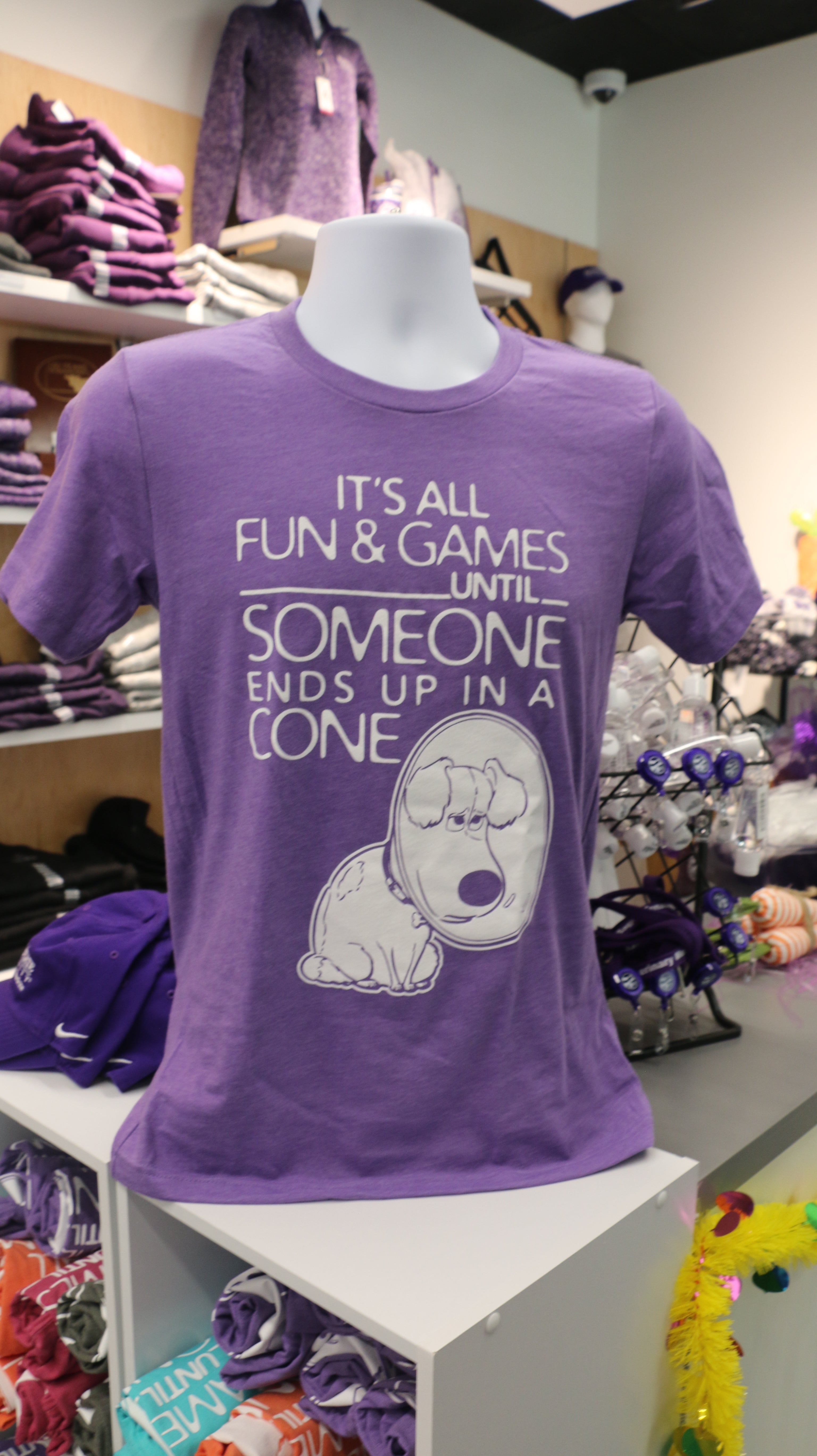 A purple Bella Canvas t-shirt with white text reading "It's all fun & games until SOMEONE ends up in a CONE" with a dog in a cone graphic design on it, displayed on a mannequin.