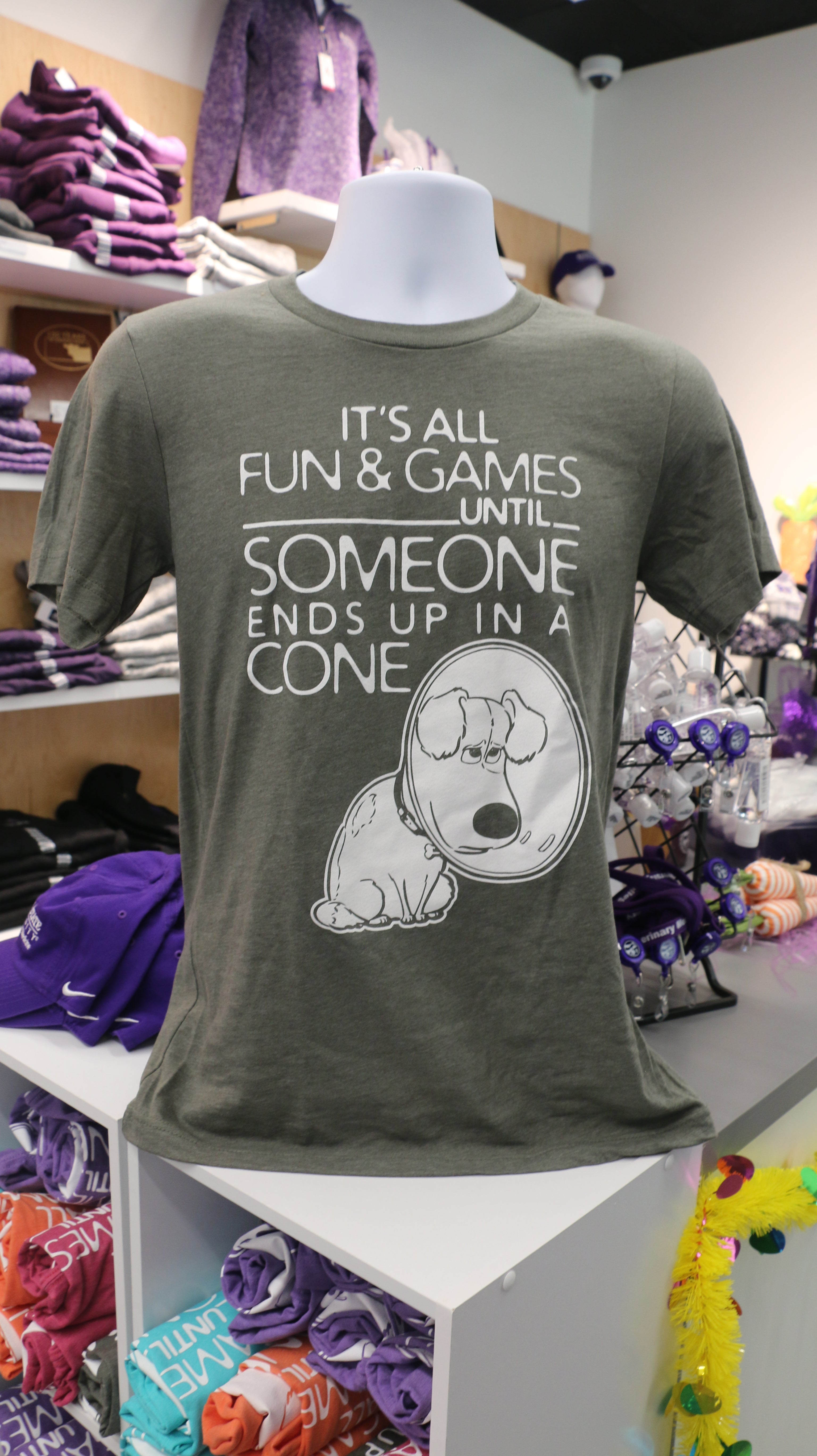 A grey Bella Canvas t-shirt with white text reading "It's all fun & games until SOMEONE ends up in a CONE" with a dog in a cone graphic design on it, displayed on a mannequin.