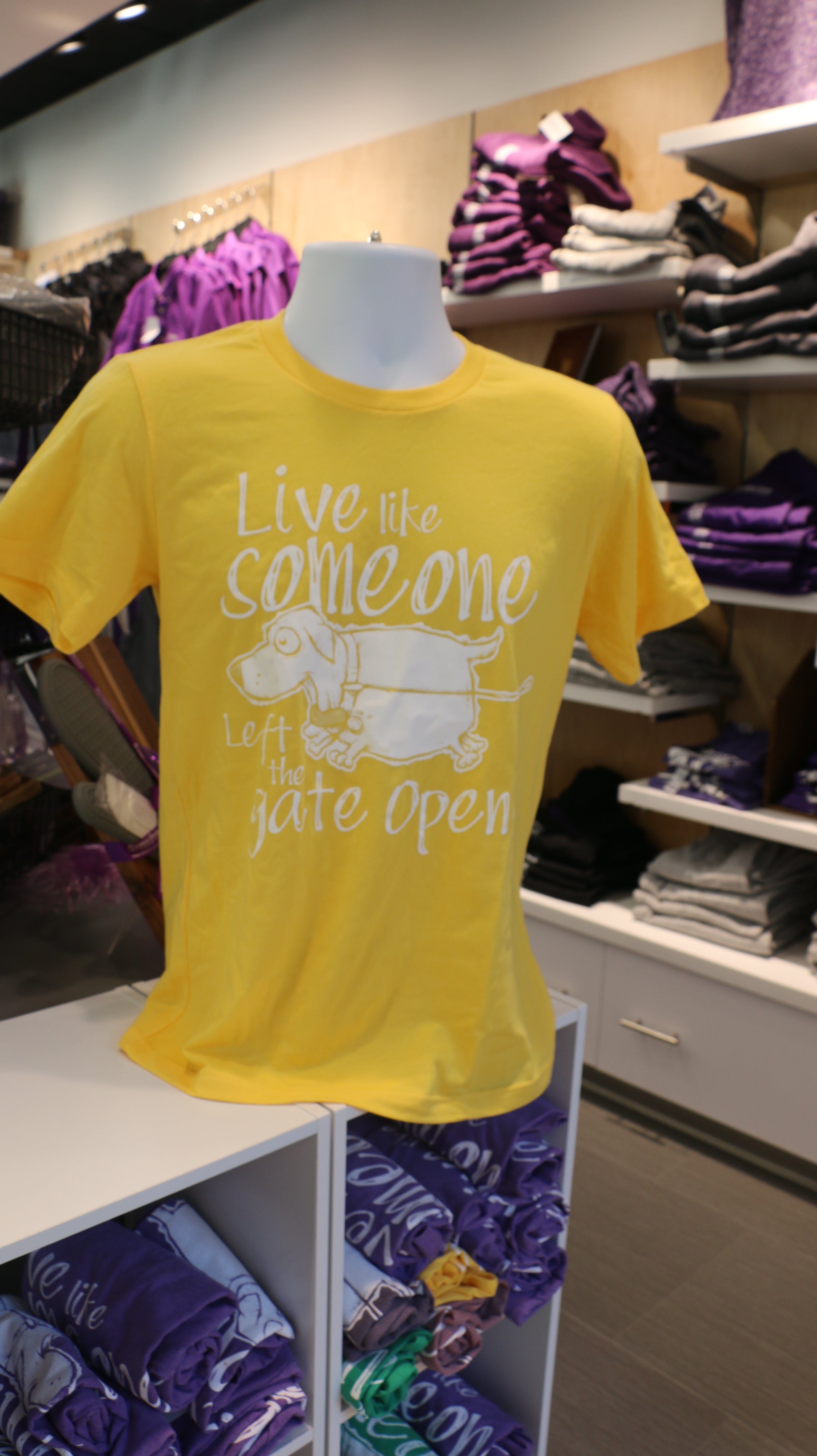 Bright yellow Bella Canvas t-shirt with white text that reads "Live like someone left the gate open!" with a dog illustration on the front.