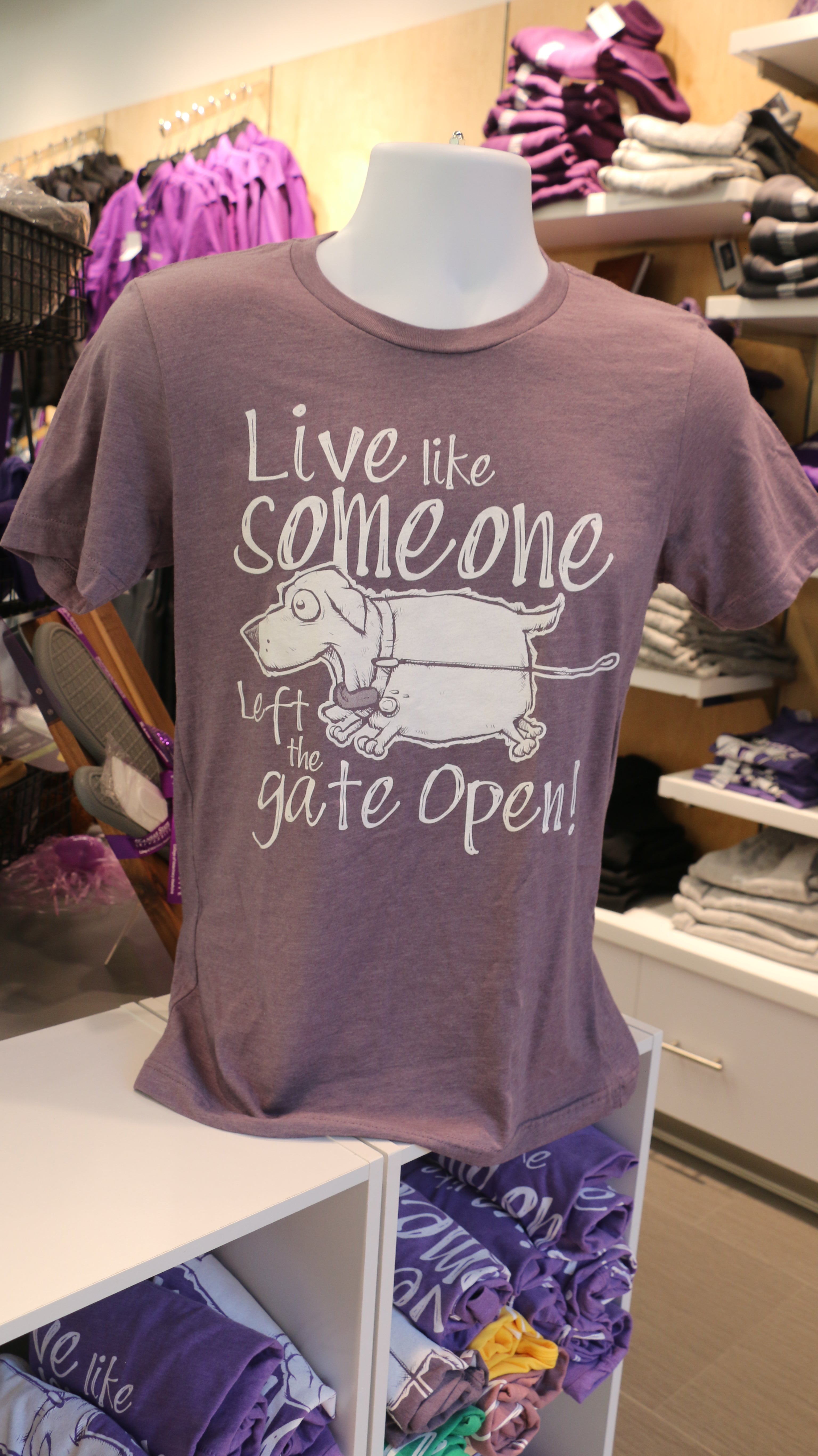 Heather purple Bella Canvas t-shirt with white text that reads "Live like someone left the gate open!" with a dog illustration on the front.