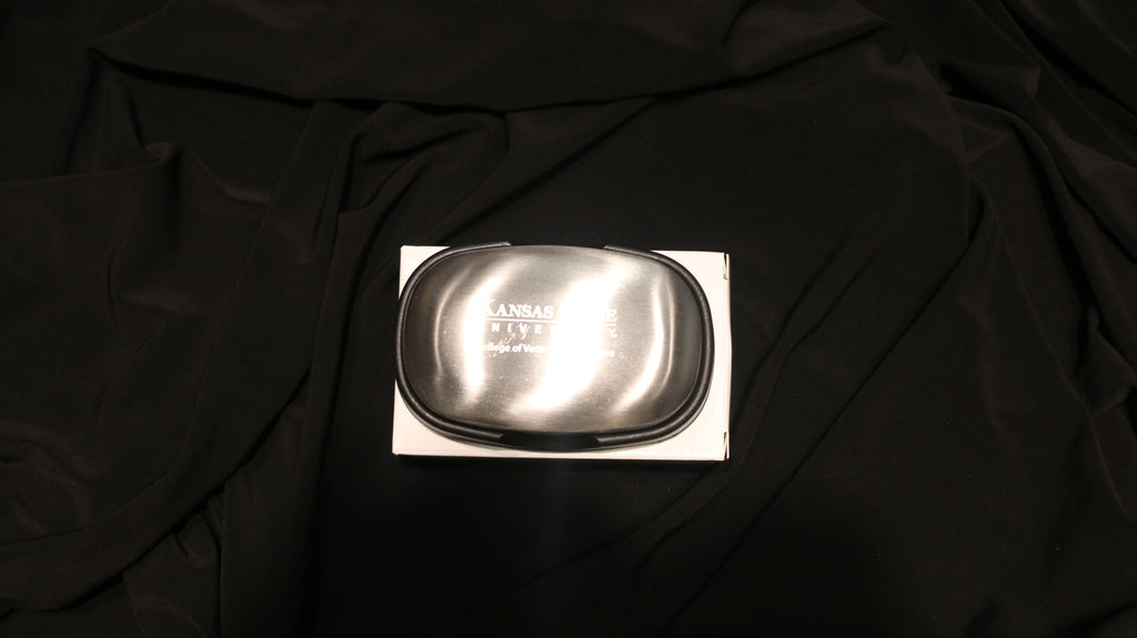 A silver steel soap bar on a black background, packaged in a cardboard box with the CVM logo engraved in the center. 