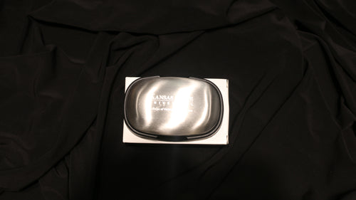 A silver steel soap bar on a black background, packaged in a cardboard box with the CVM logo engraved in the center. 