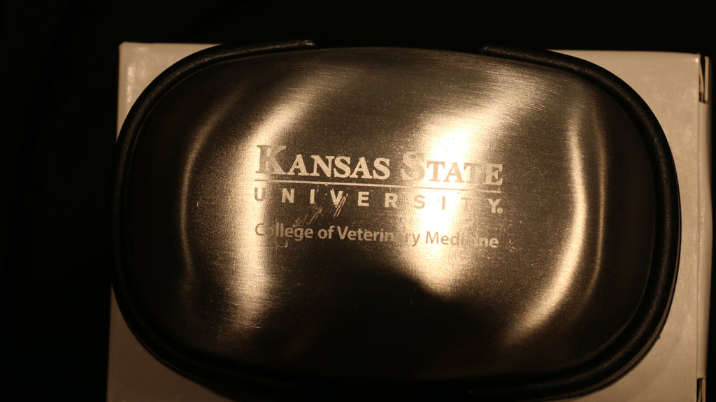 A silver steel soap bar packaged in a cardboard box with "Kansas State University College of Veterinary Medicine" engraved in the center. 