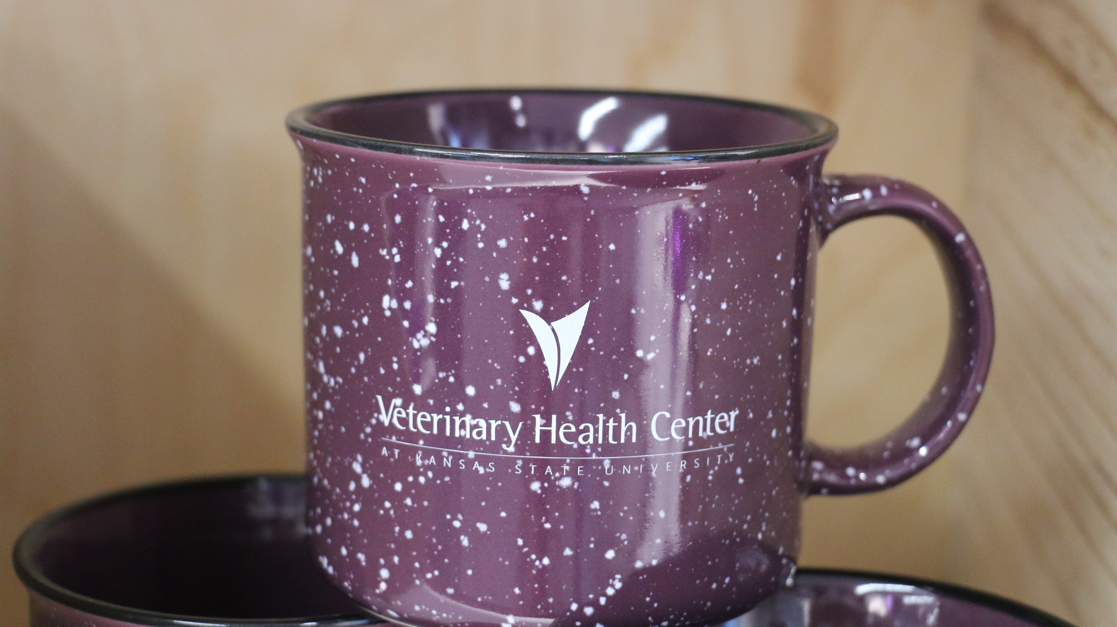 A purple ceramic campfire mugs with white speckled patterns and the Veterinary Health Center logo. 