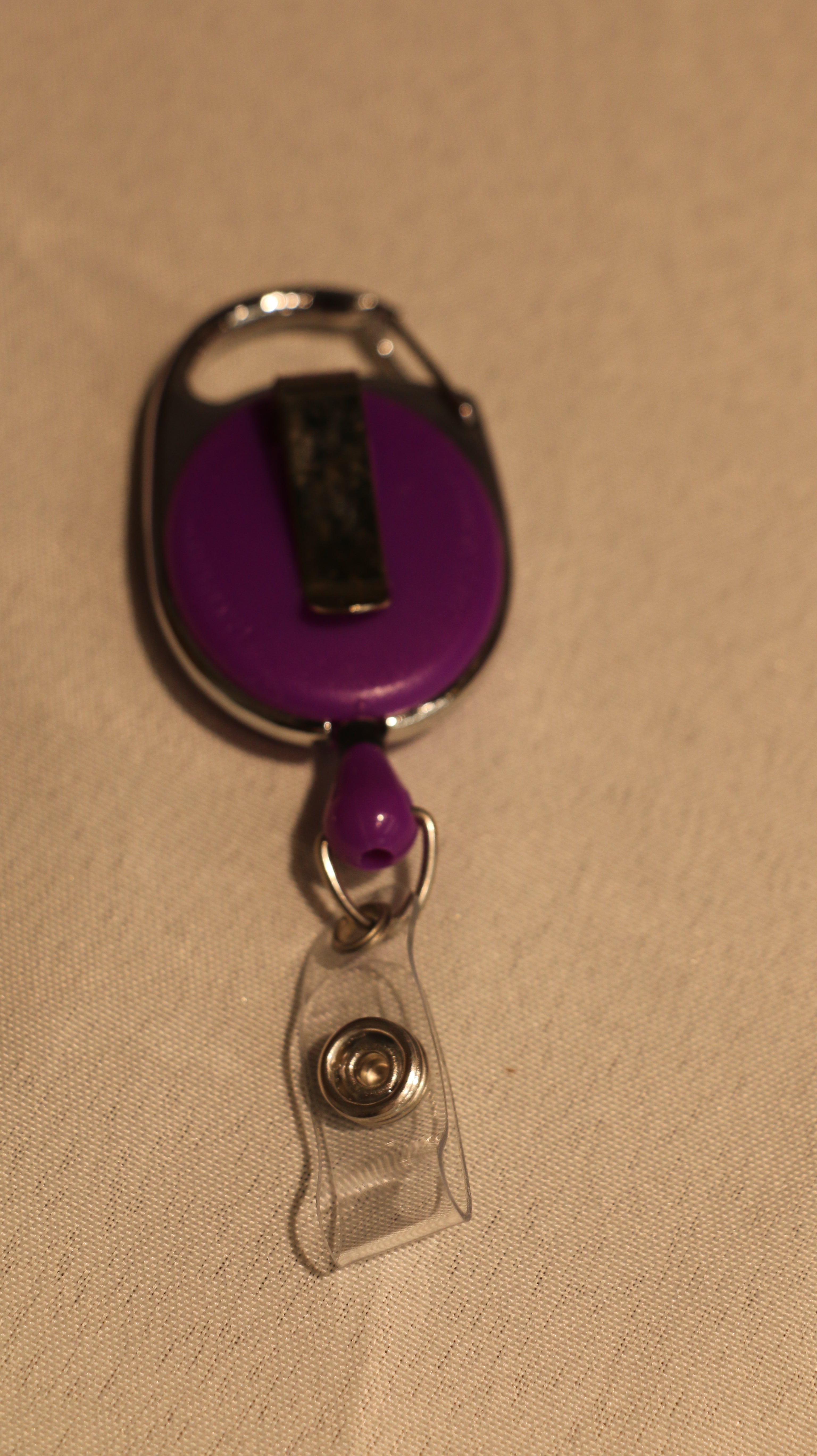 The back of the purple retractable badge holder and its chrome clip
