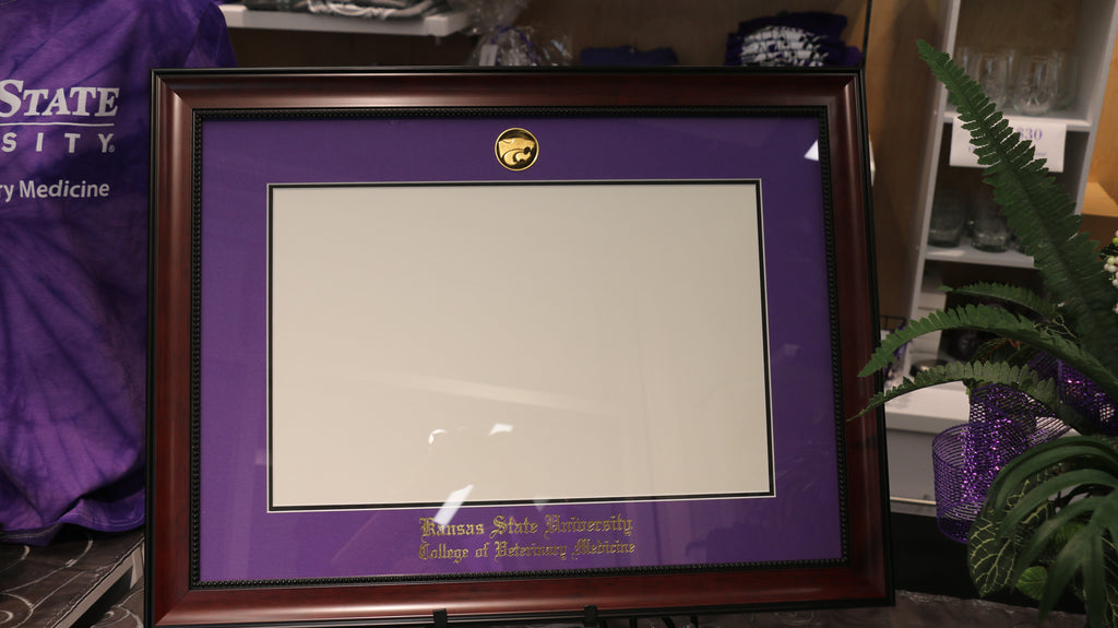 A diploma frame with an avalon mahogany finish, purple primary mat, and black accent mat. It features an imprint of Kansas State University College of Veterinary Medicine and a gold plated power cat logo.