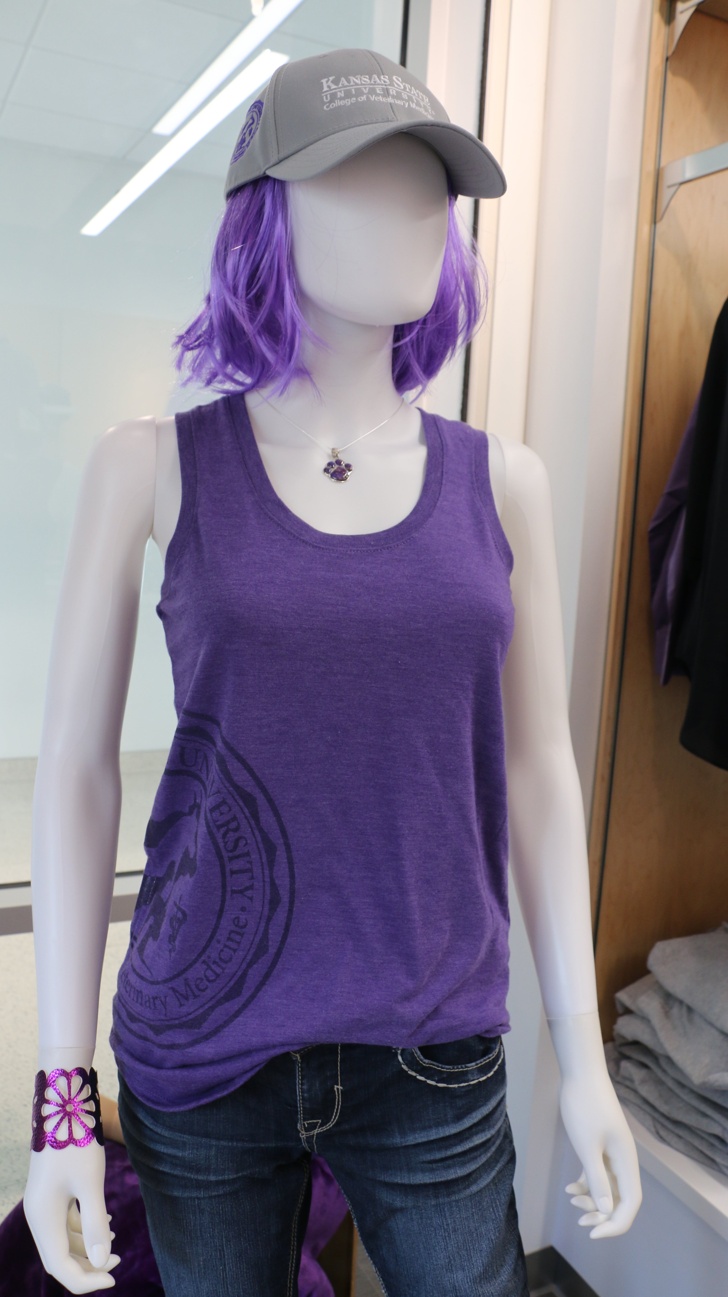 A mannequin wearing a purple District Women's Racerback Tank Top with a CVM seal engraving on the bottom right side. 