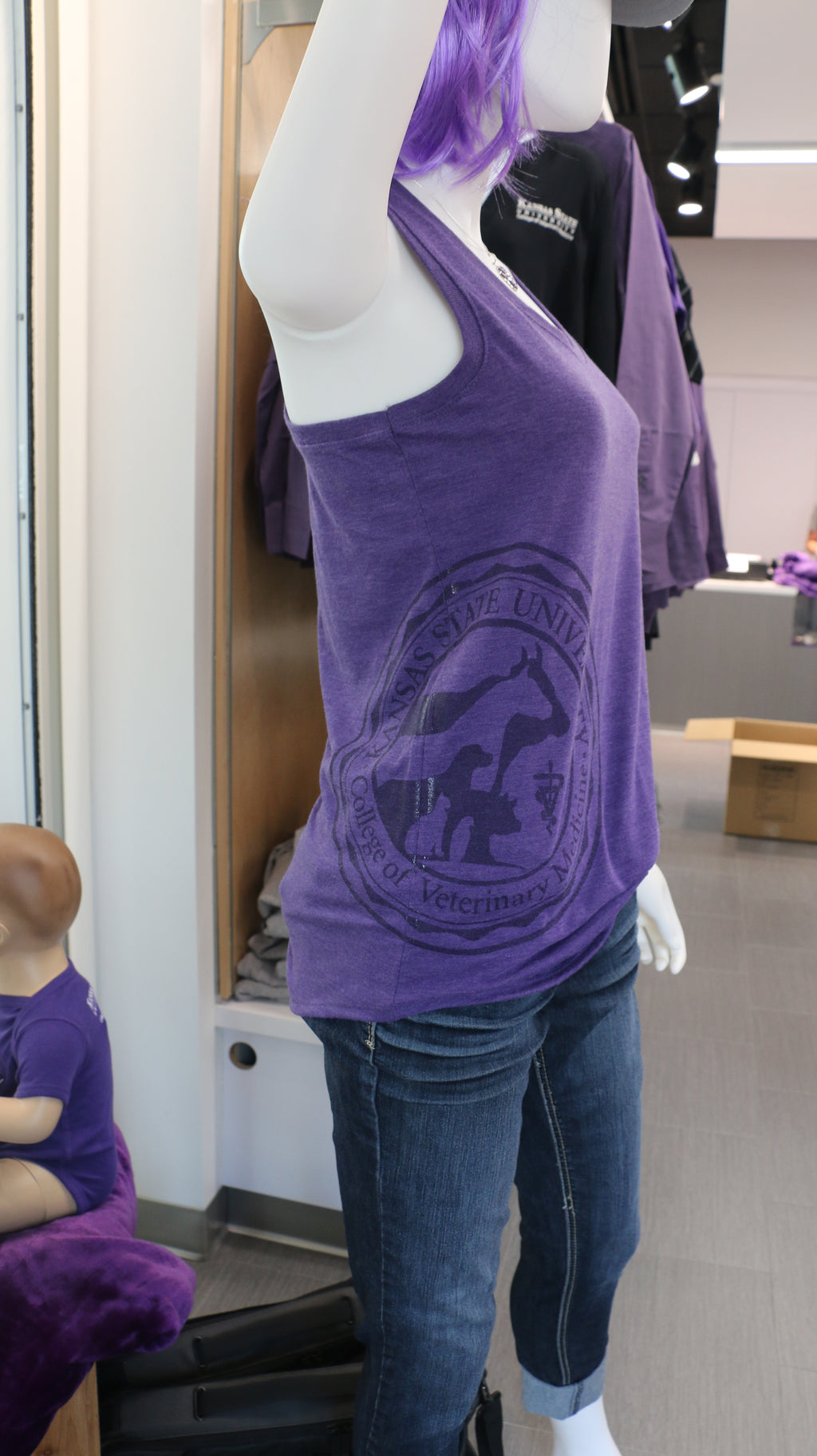 A mannequin wearing a purple District Women's Racerback Tank Top with a CVM seal engraving on the bottom right side. 