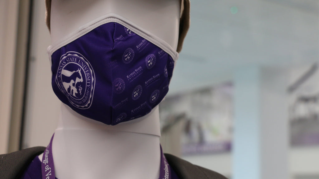 A purple face mask displayed on a mannequin head, featuring a 3-layer design with a filter pocket, nose clip, and an adjustable elastic band.