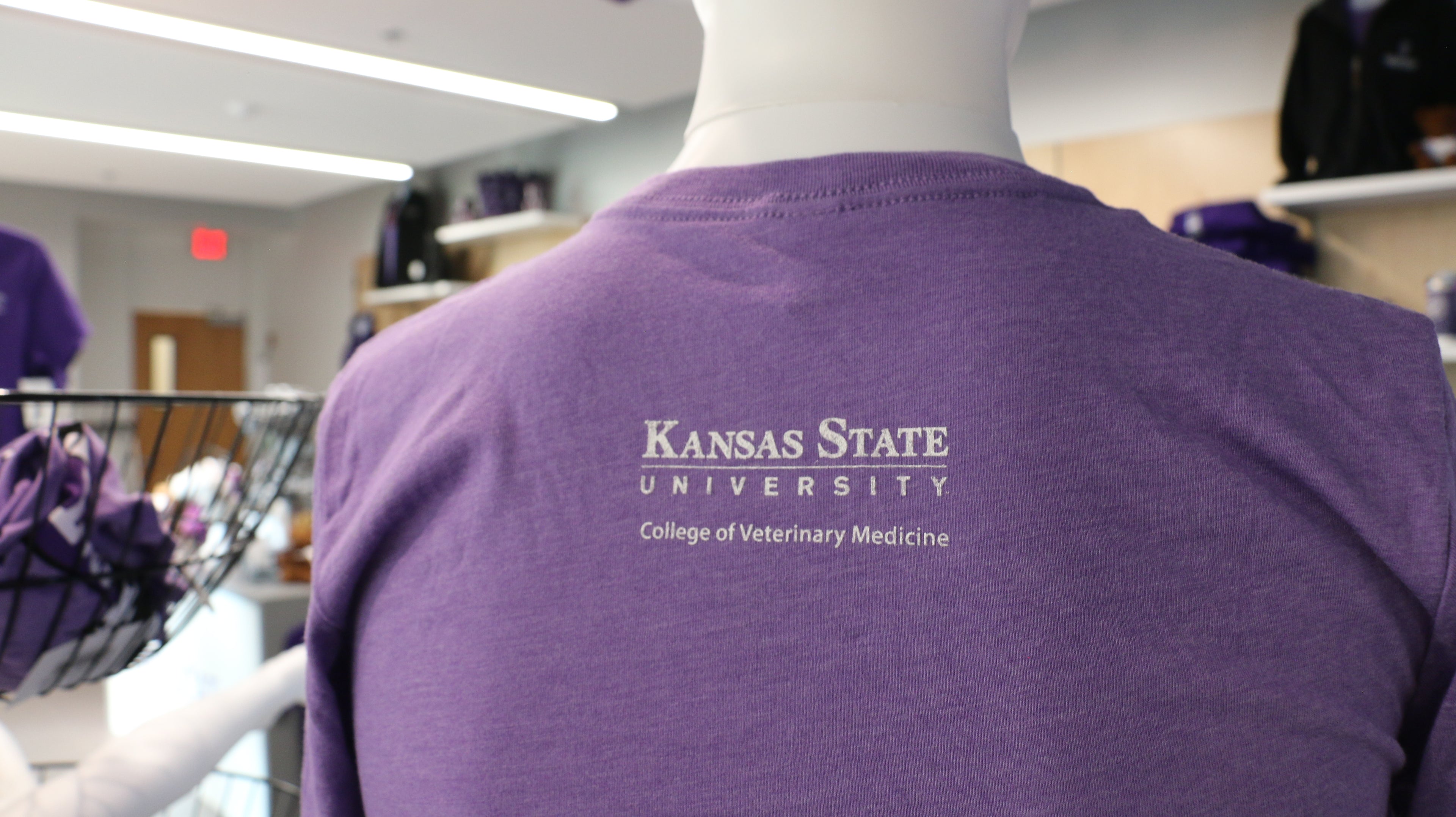 A rear view of the shirt where Kansas State University College of Veterinary Medicine is printed in white in the upper middle back area. 