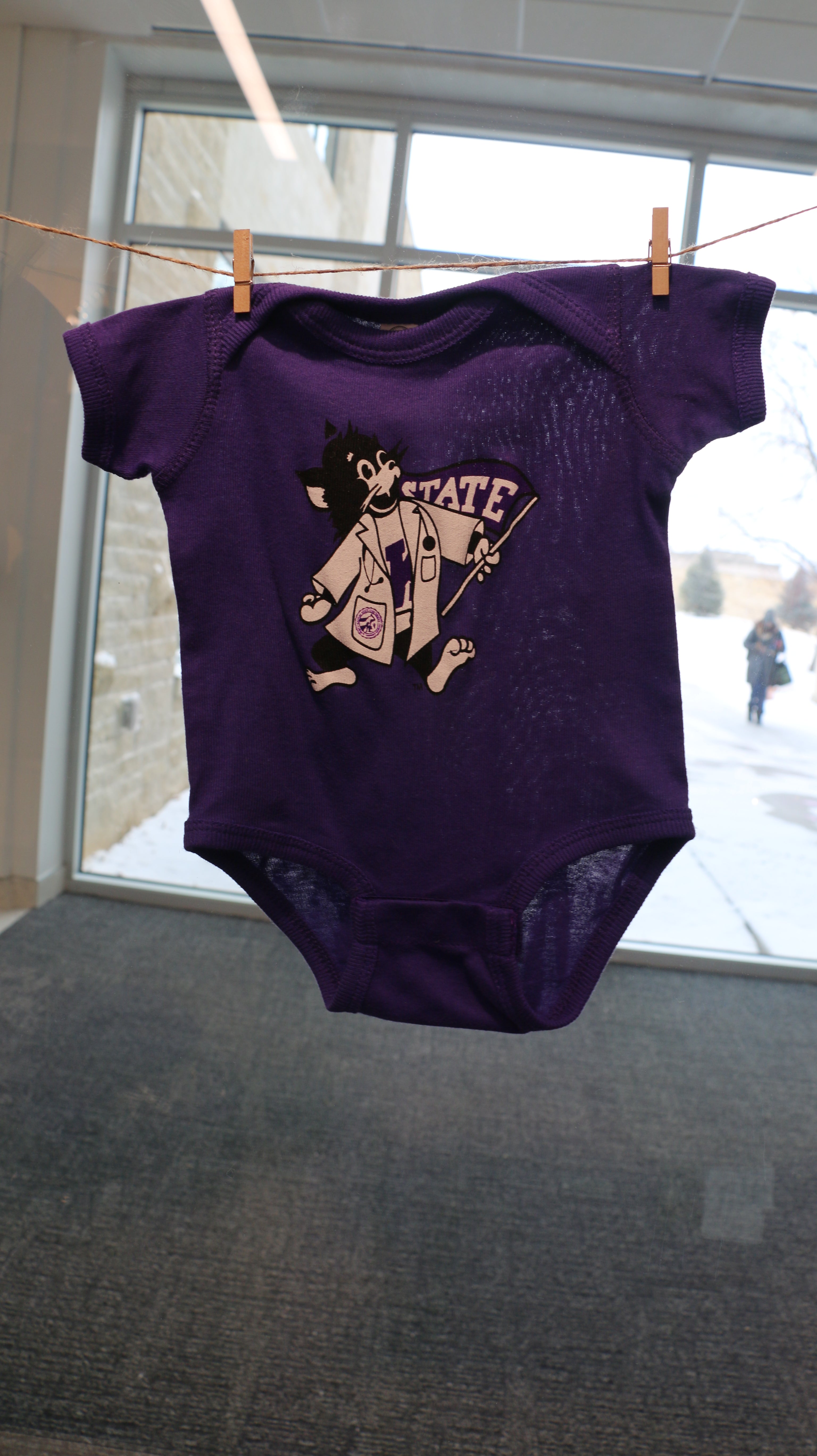 An infant short sleeve onesie with a graphic print of Labcoat Willie on a hanger. 