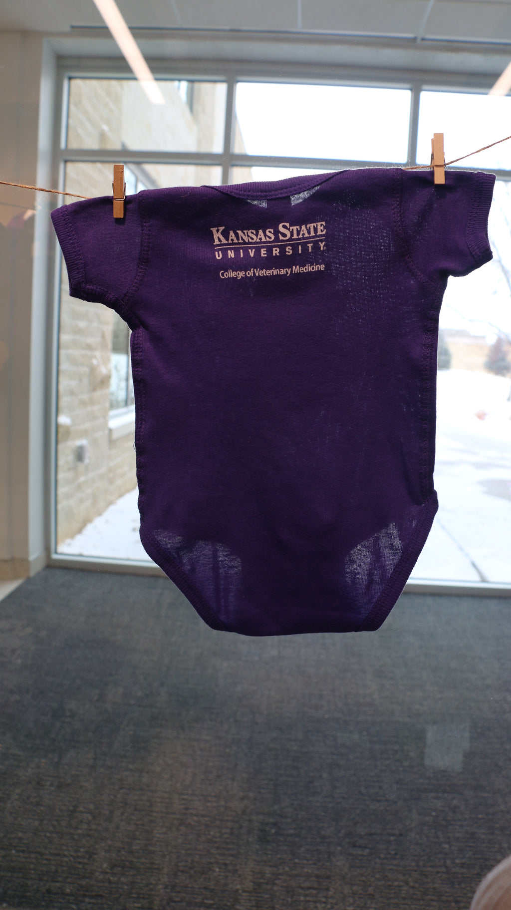 A rear view of the onesie with a white CVM logo in the upper middle back area. 