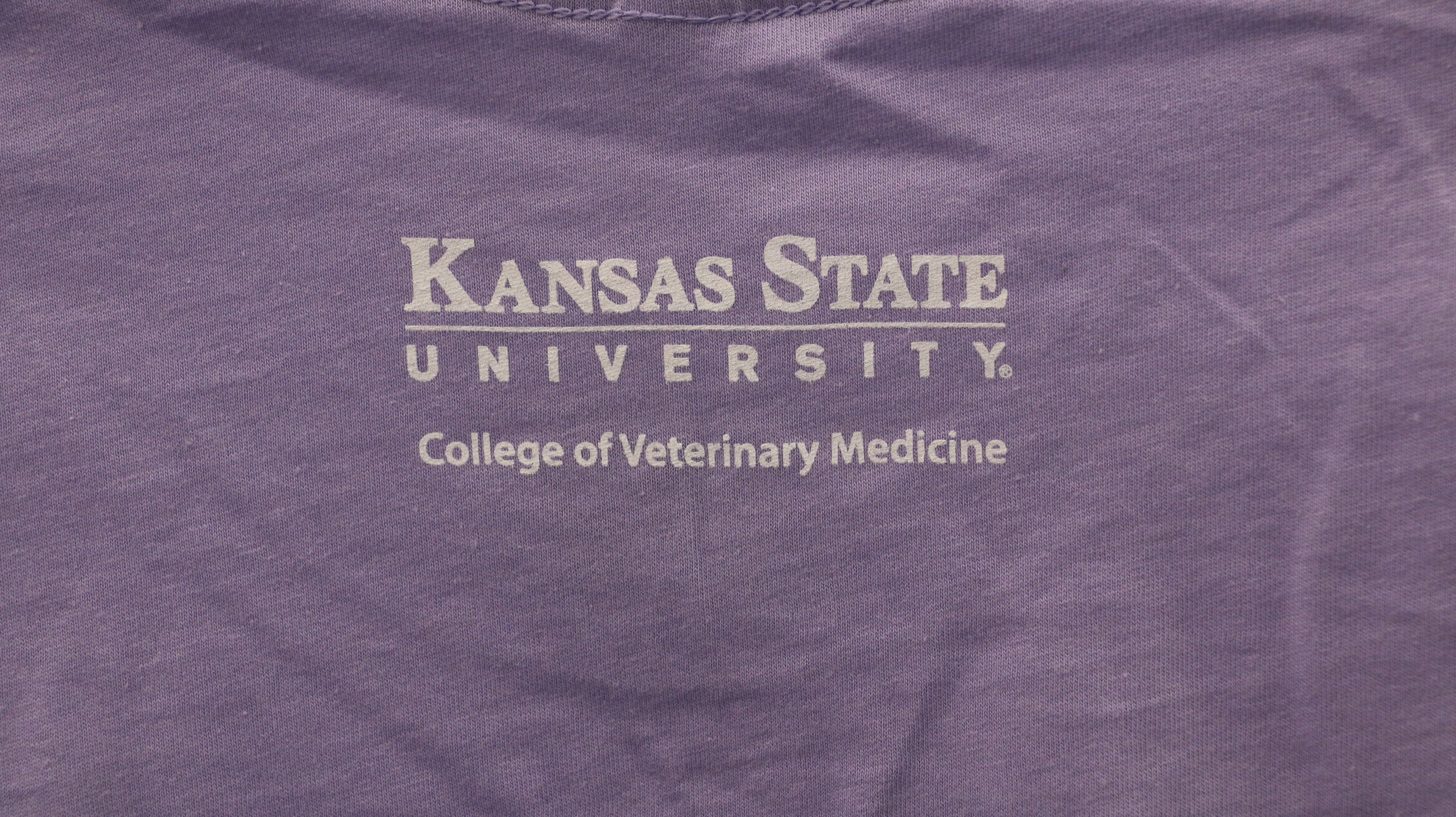 A rear view of the white CVM lettering on the upper middle bac of the shirt. 