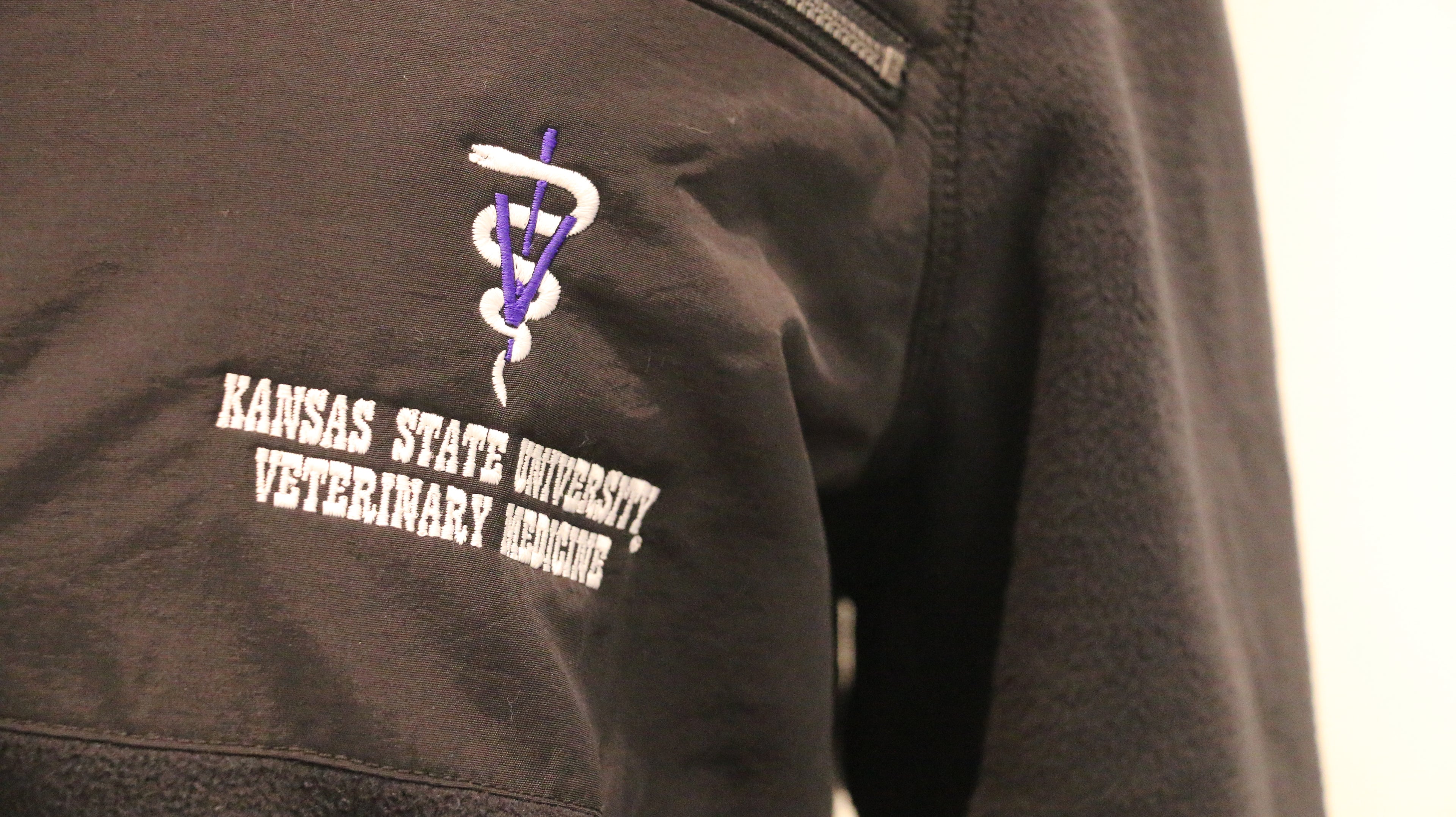 A close-up of the white lettering "Kansas State University Veterinary Medicine" on the upper left chest area. 