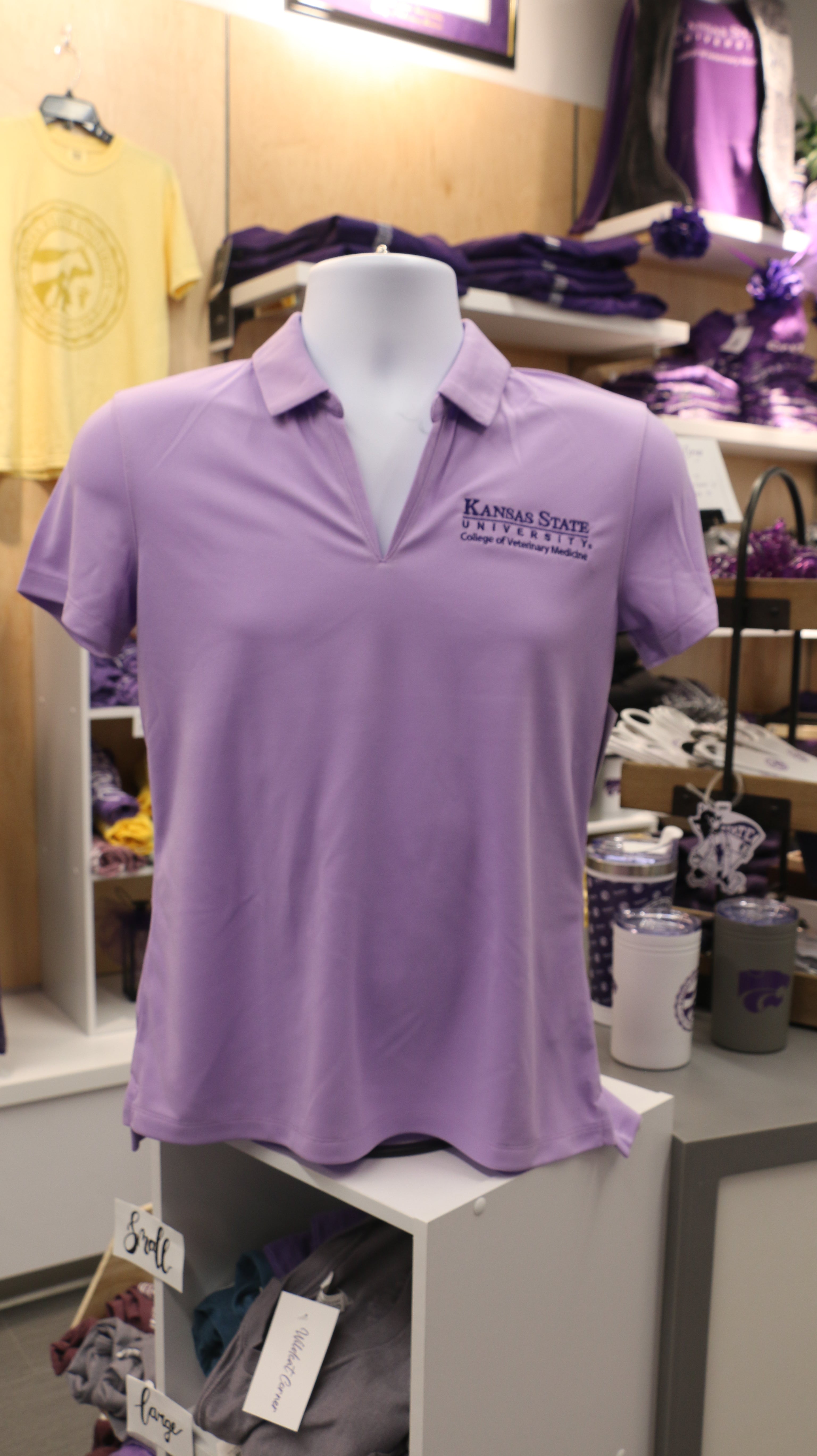 A lavender-colored Nike ladies polo shirt with a dark purple K-State CVM logo displayed on a mannequin.