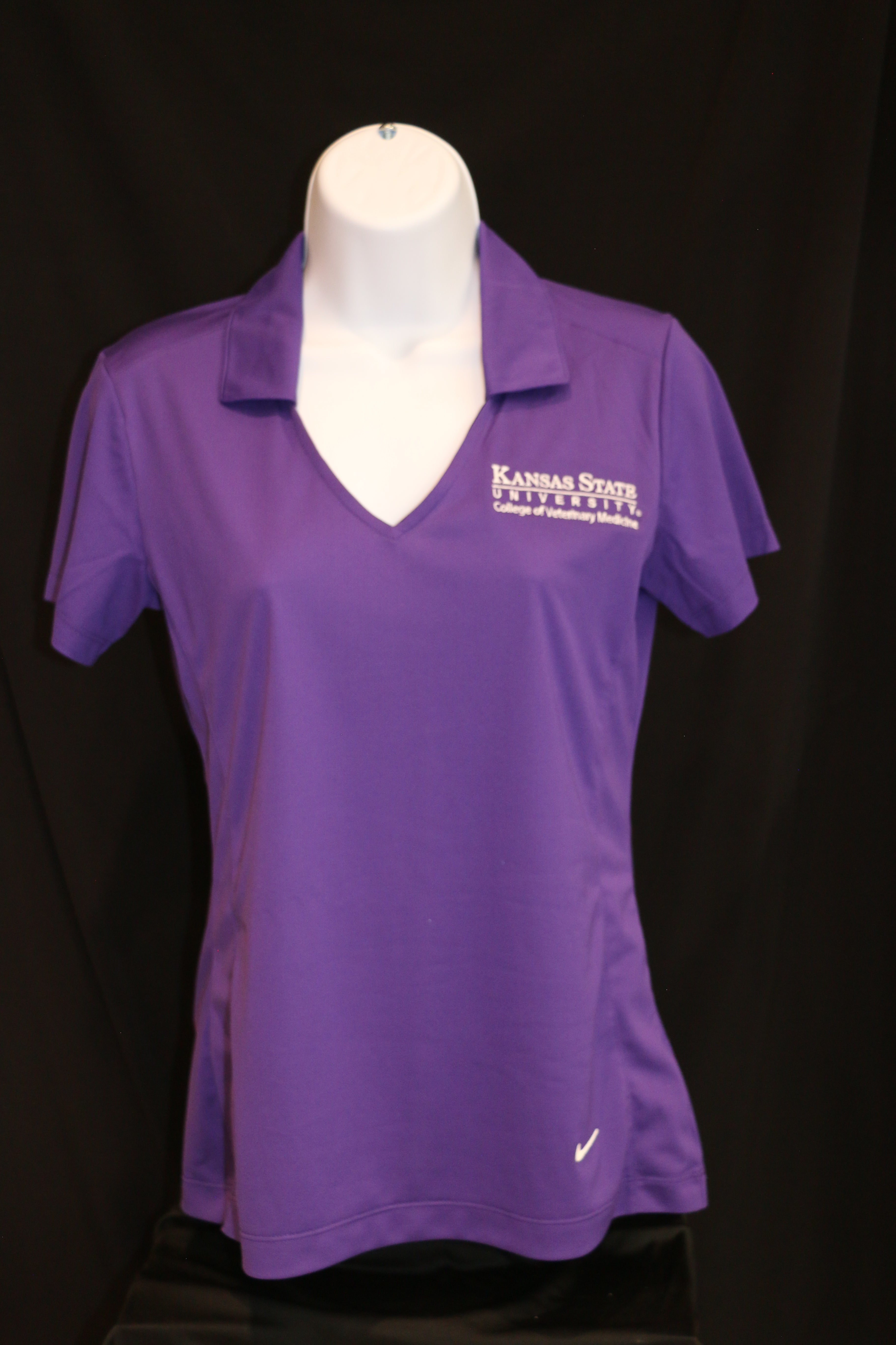 A purple Nike ladies polo shirt with a white CVM logo, collar, and V-neck, displayed on a mannequin.