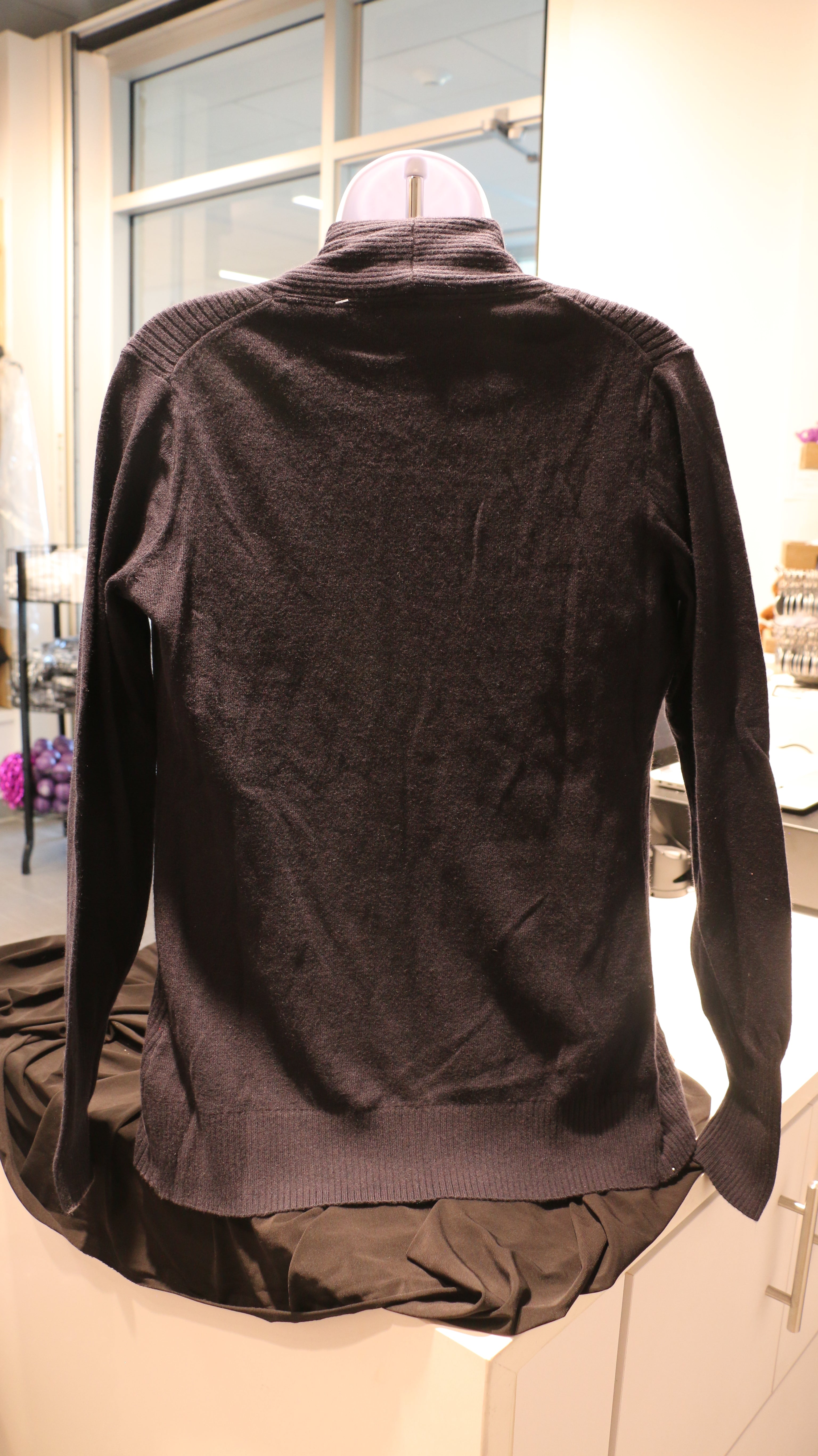 A rear view of the lady's port authority ribbed black cardigan.