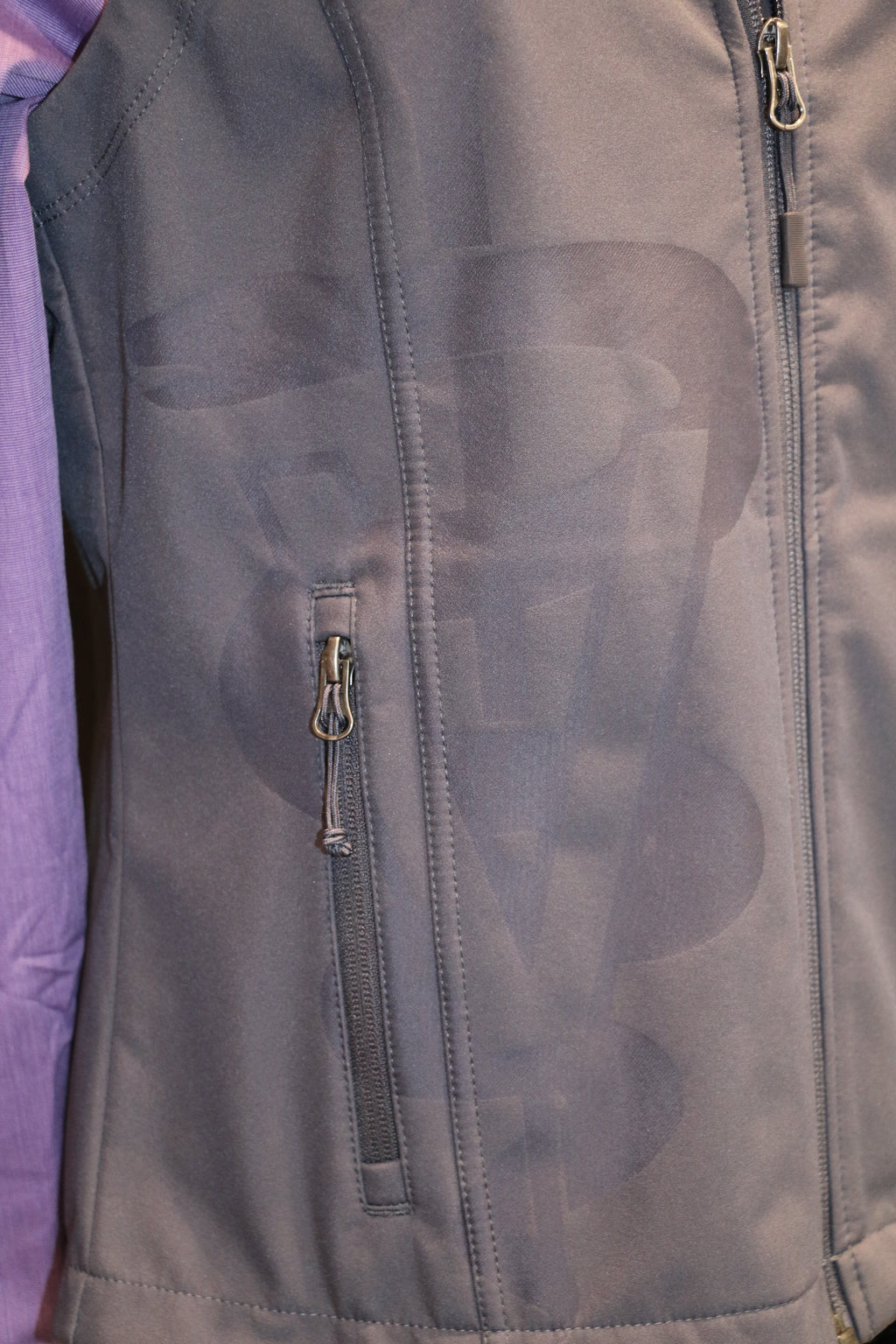A close-up view of the grey laser caduceus on the bottom right side of the vest. 
