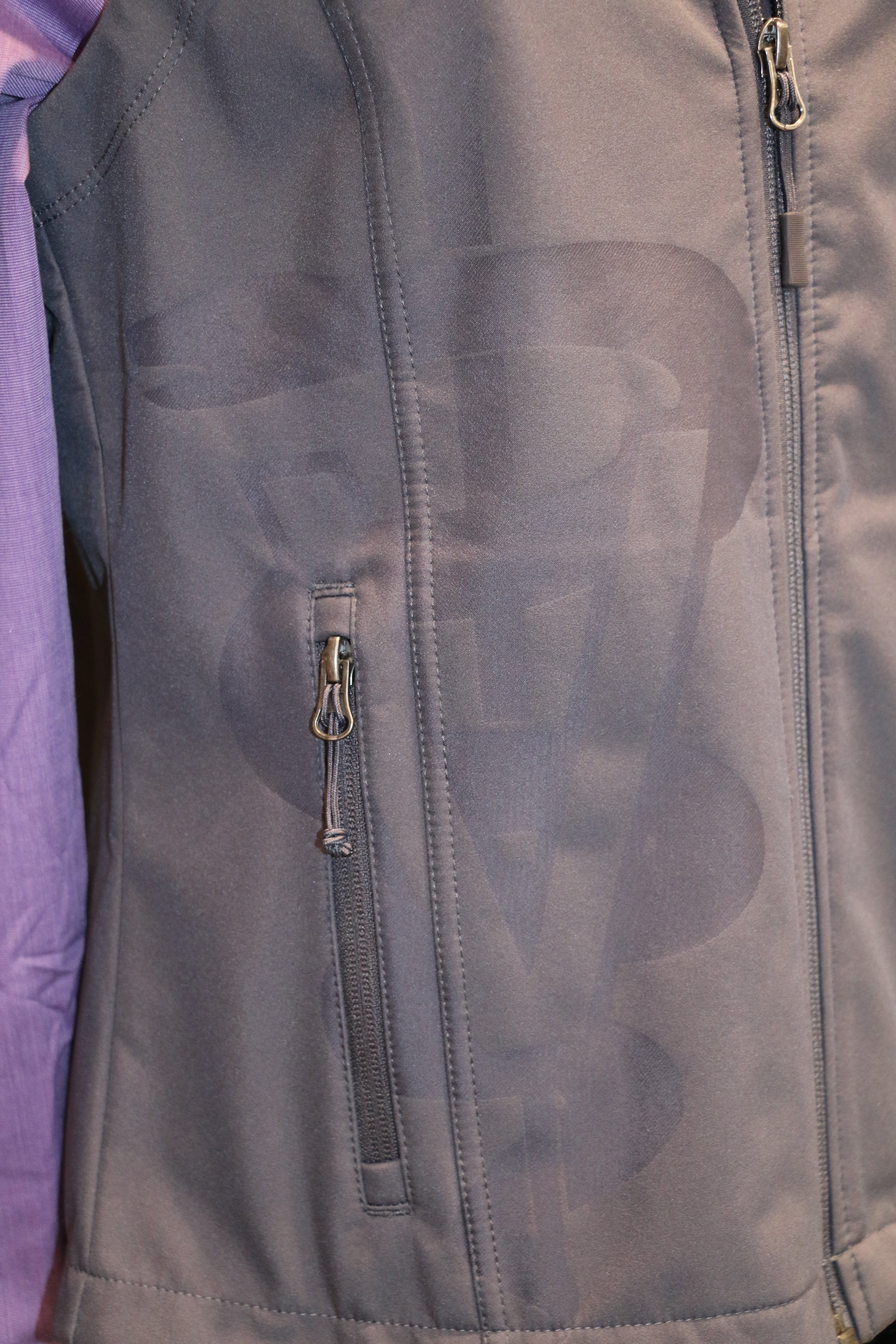 A close-up view of the grey laser caduceus on the bottom right side of the vest. 