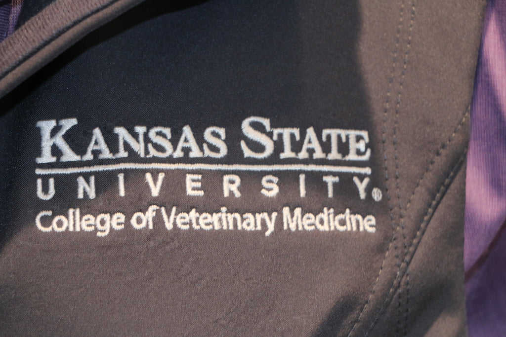 A close-up view of the white CVM logo on the upper left side of the vest. 
