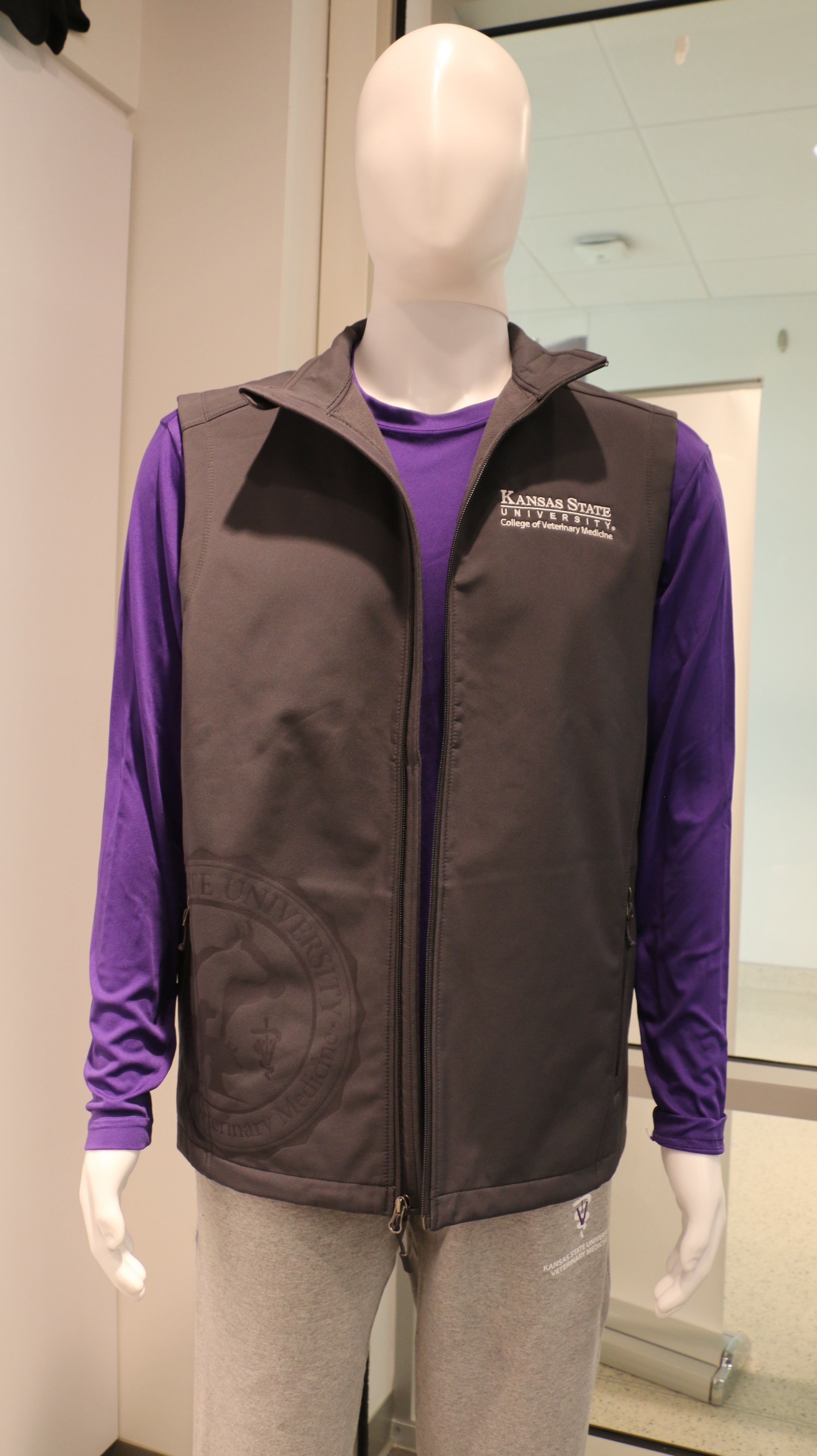 A gray Port Authority lightweight vest for ladies displayed on a mannequin, featuring side zip pockets and a college seal laser etching.