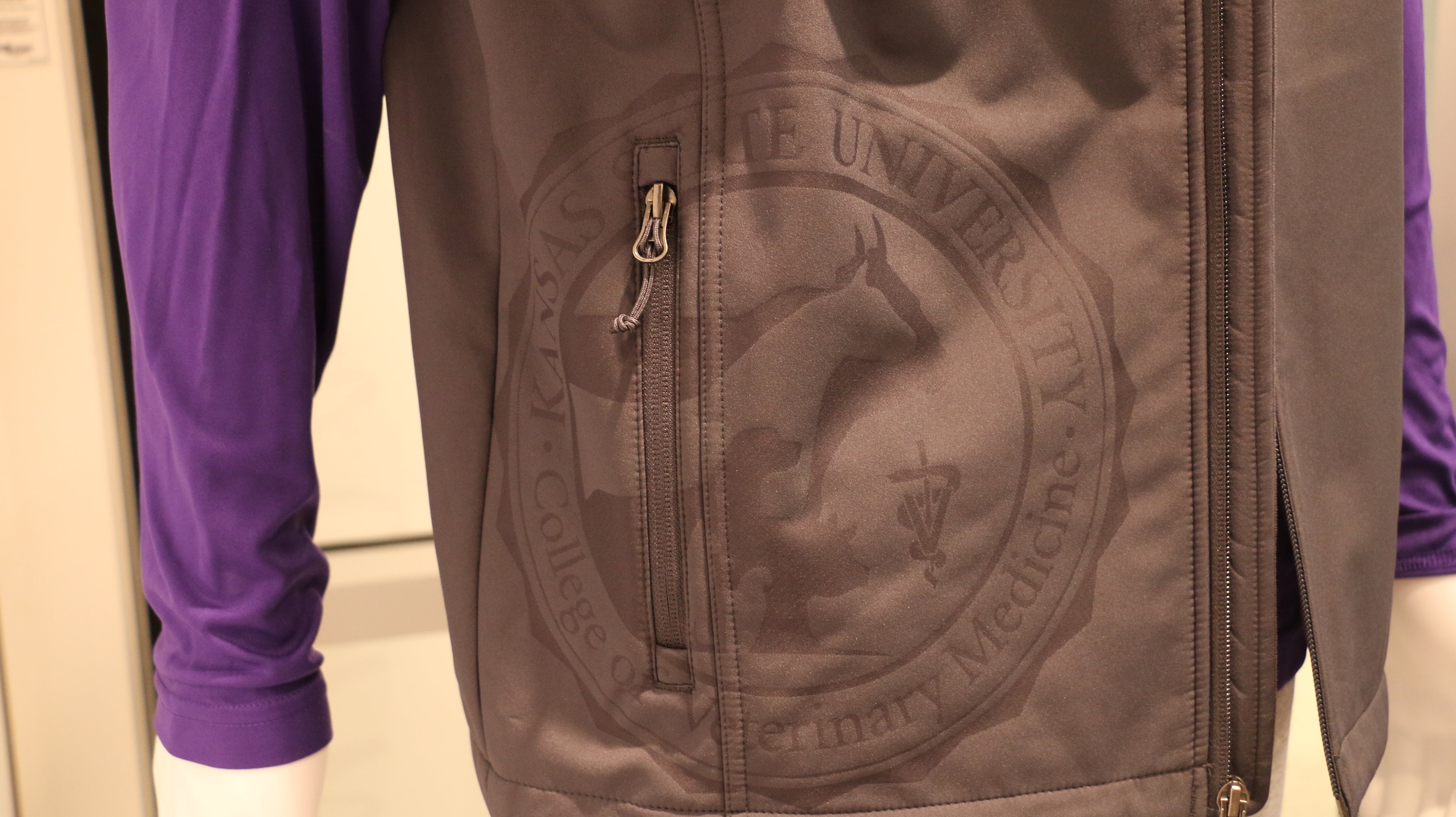 A close-up of the college seal laser etching on the bottom right of the vest. 