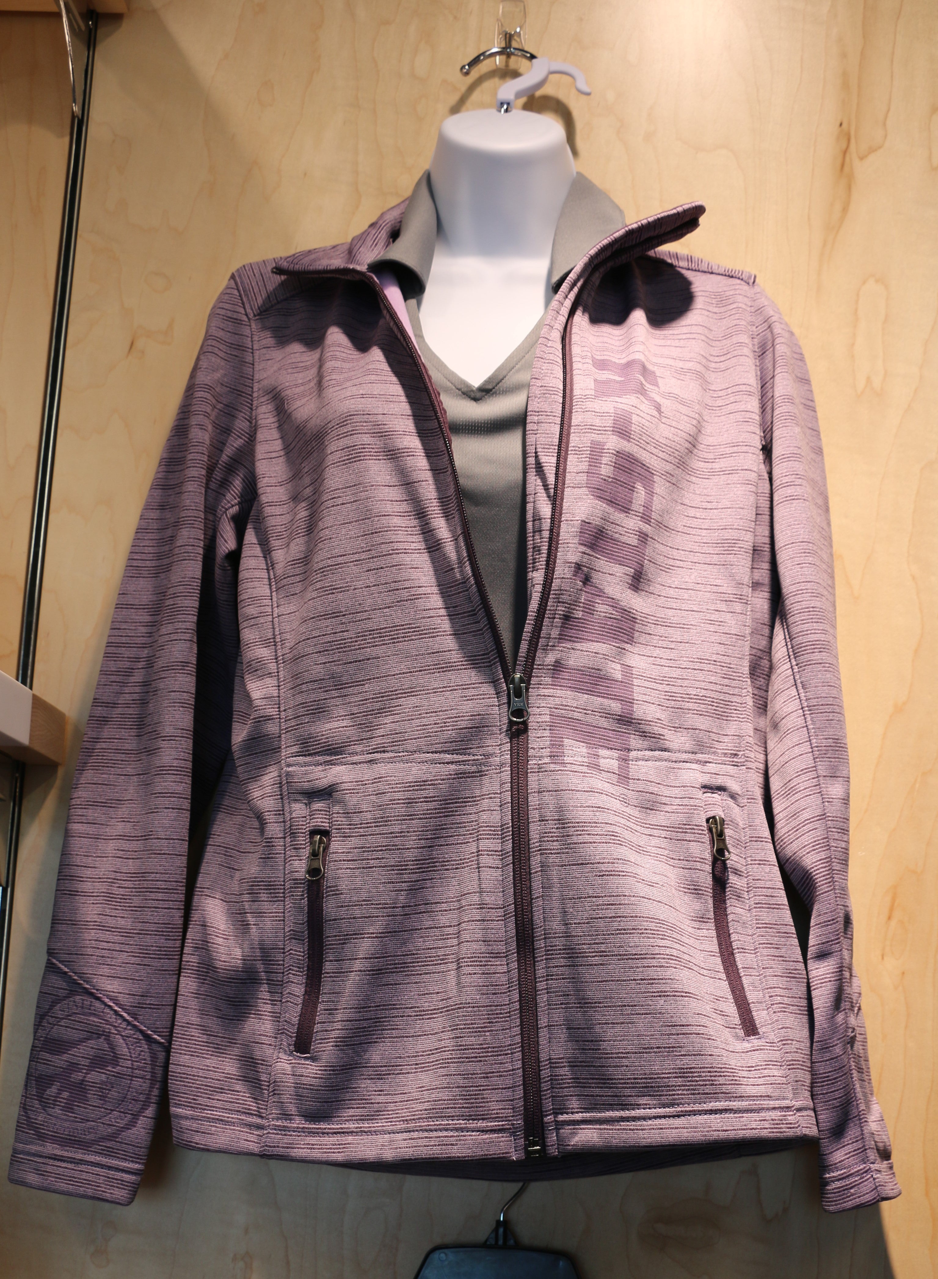 A purple fleece jacket with digital stripe pattern, featuring a laser etched college seal on the cuff and K-State laser etched down the front, displayed on a mannequin.